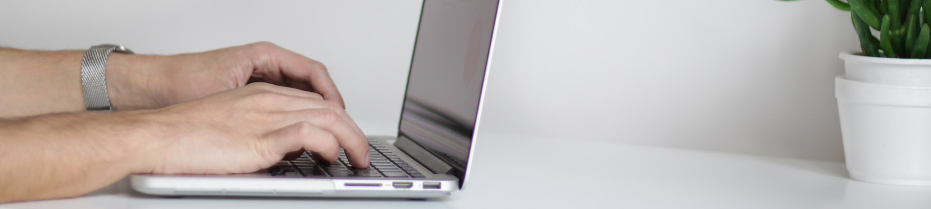 A photo of two hands typing on the keyboard of a laptop computer