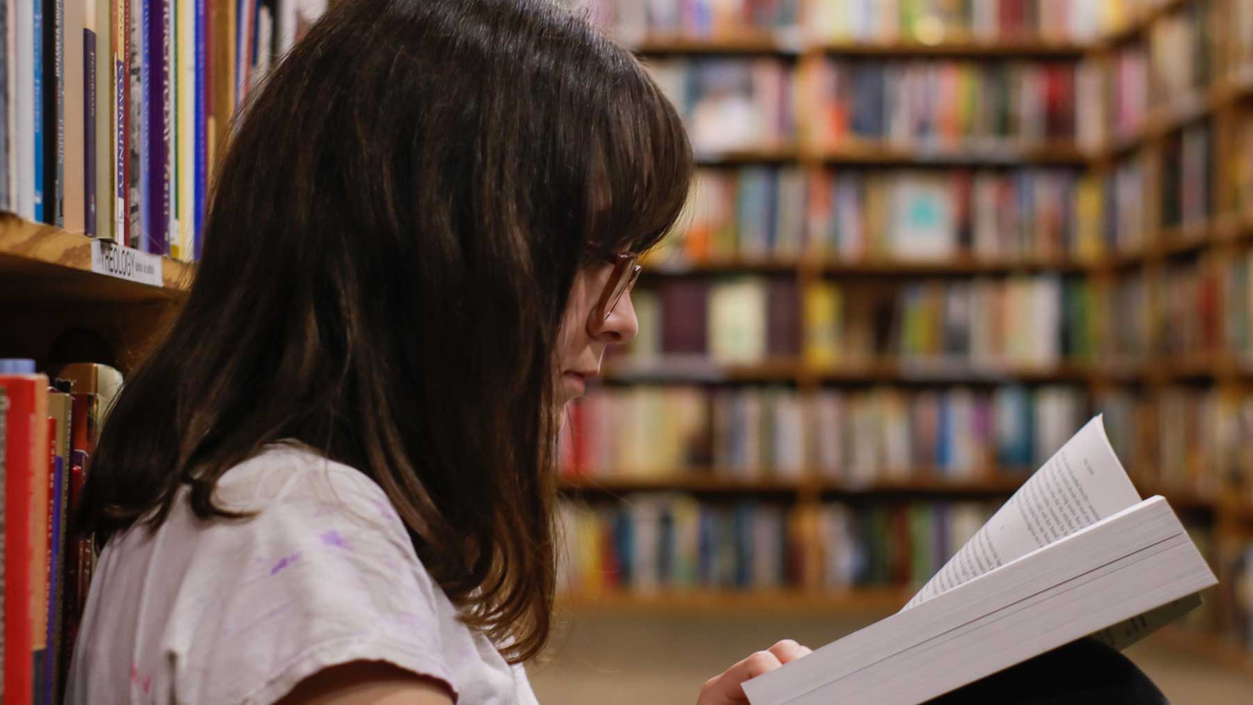 college student reading book in library